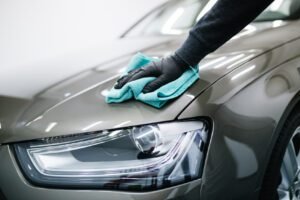 A man cleaning car with microfiber cloth, car detailing (or valeting) concept. Selective focus.